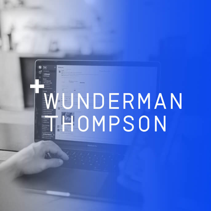 A person typing on a laptop with the Wunderman Thompson logo on the side.